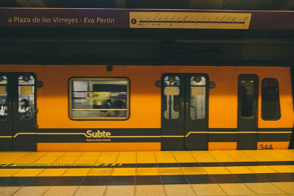 a yellow subway train stopped at a train station