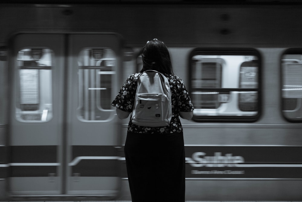 uma mulher em pé na frente de um trem do metrô