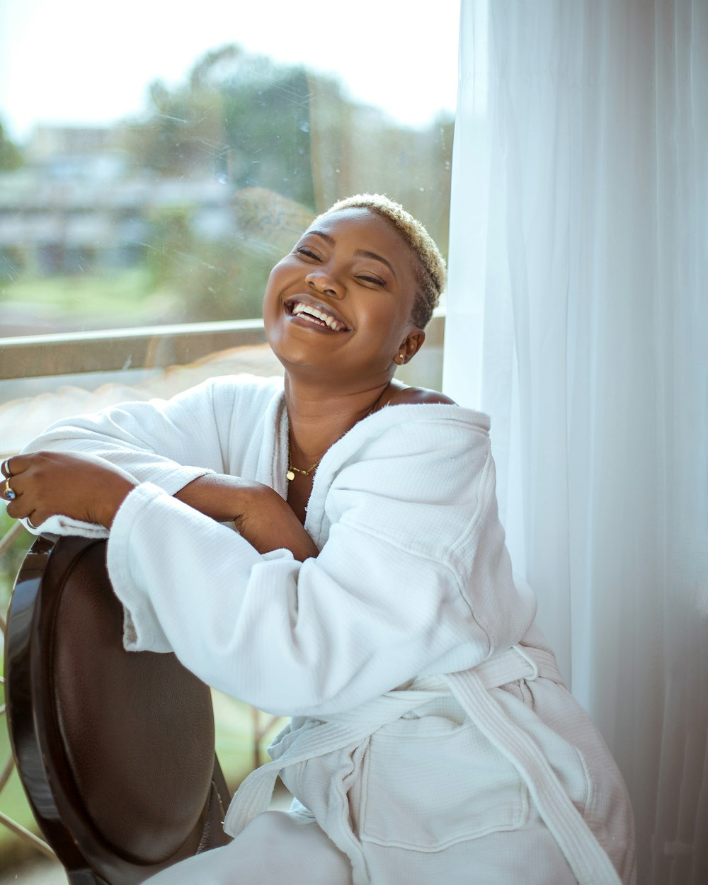 a woman in a bathrobe sitting by a window