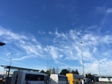 A fleet of buses parked at a well-organized depot under clear skies.