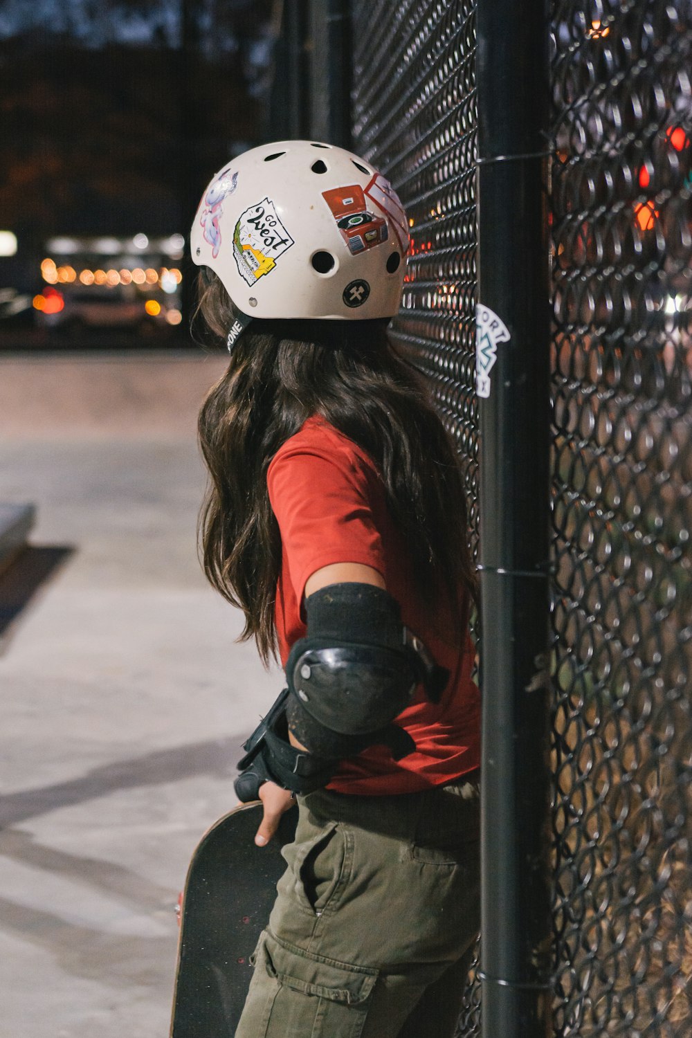 a person with a skateboard leaning against a fence