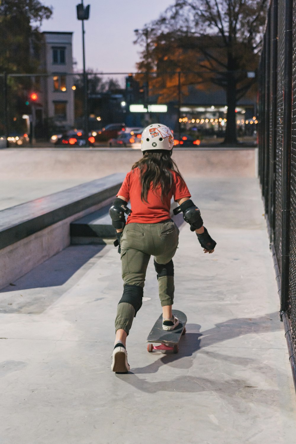 a young girl riding a skateboard down a sidewalk