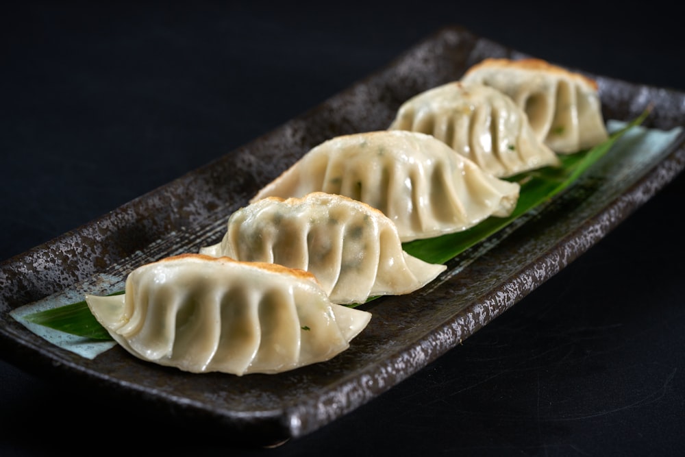 three dumplings are sitting on a black plate