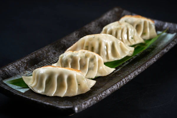 Tiga dumpling di pinggan hitam