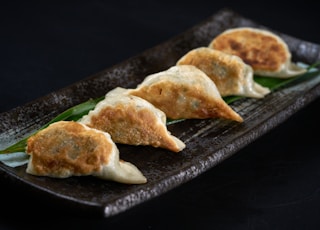 a black plate topped with three dumplings of food