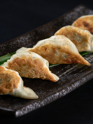 a black plate topped with three dumplings of food