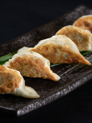 a black plate topped with three dumplings of food