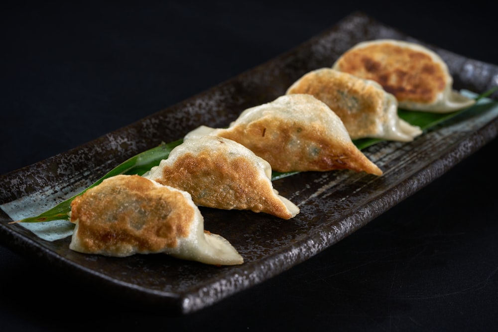 a black plate topped with three dumplings of food