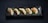 Five pan-fried dumplings are neatly arranged on a long, rectangular, dark ceramic plate. A green leaf lies beneath the dumplings, adding a contrasting element to the presentation. The dumplings have a golden-brown, crispy side while the top is a lighter, steamed texture.