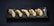 Five pan-fried dumplings are neatly arranged on a long, rectangular, dark ceramic plate. A green leaf lies beneath the dumplings, adding a contrasting element to the presentation. The dumplings have a golden-brown, crispy side while the top is a lighter, steamed texture.