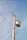 A utility pole with multiple electrical wires extending outward against a clear blue sky. At the top of the pole, there is a transformer and several insulators holding the wires in place.