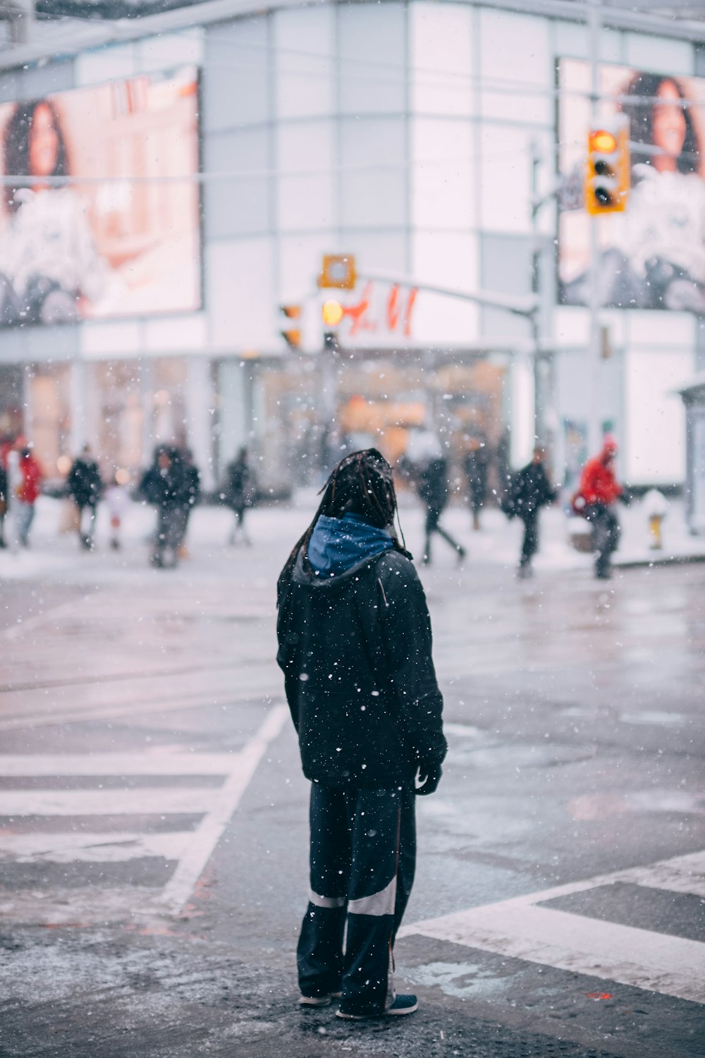a person standing on a street corner in the snow
