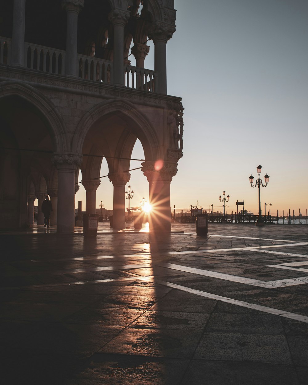 the sun is setting behind a large building