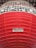 A large red lantern with horizontal ridges and Japanese characters in black printed in horizontal lines on a white background near the top. A label with more Japanese text is visible on a lower part of the lantern.