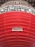 A large red lantern with horizontal ridges and Japanese characters in black printed in horizontal lines on a white background near the top. A label with more Japanese text is visible on a lower part of the lantern.