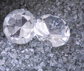 two diamonds sitting on top of a pile of crushed glass