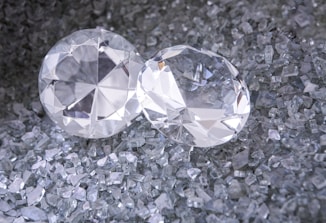 two diamonds sitting on top of a pile of crushed glass