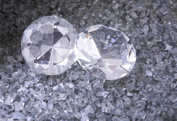 two diamonds sitting on top of a pile of crushed glass