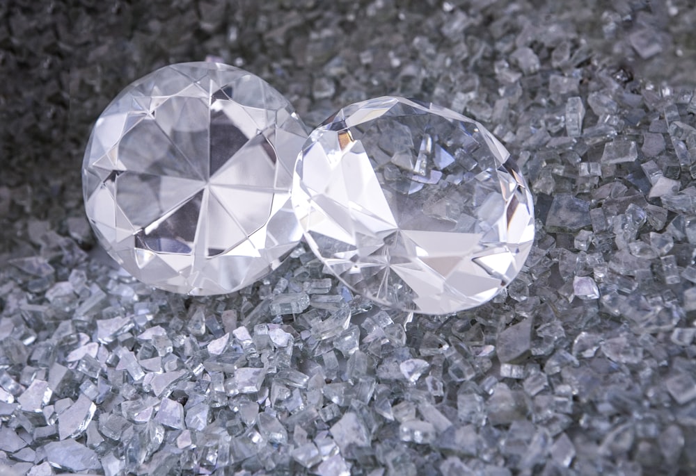 two diamonds sitting on top of a pile of crushed glass