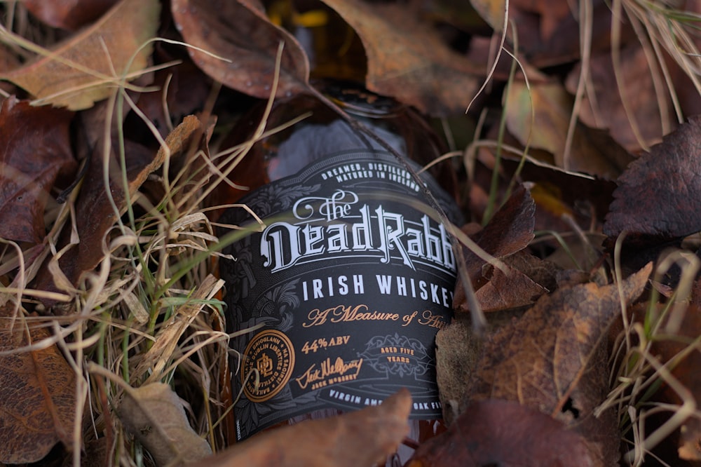 a bottle of dead rabbit irish whiskey surrounded by leaves