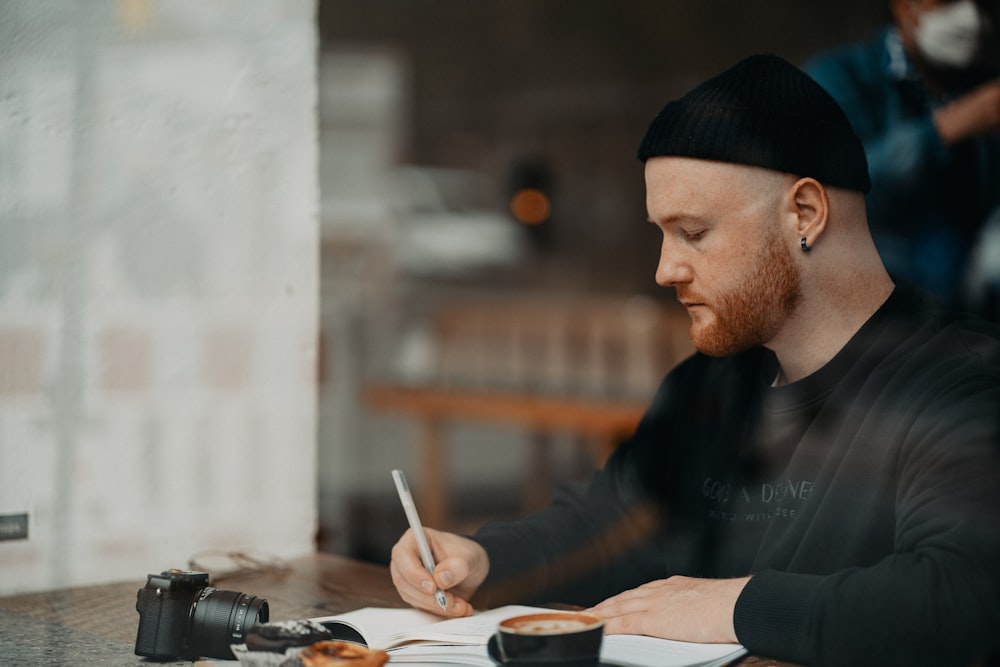 a man sitting at a table writing on a piece of paper