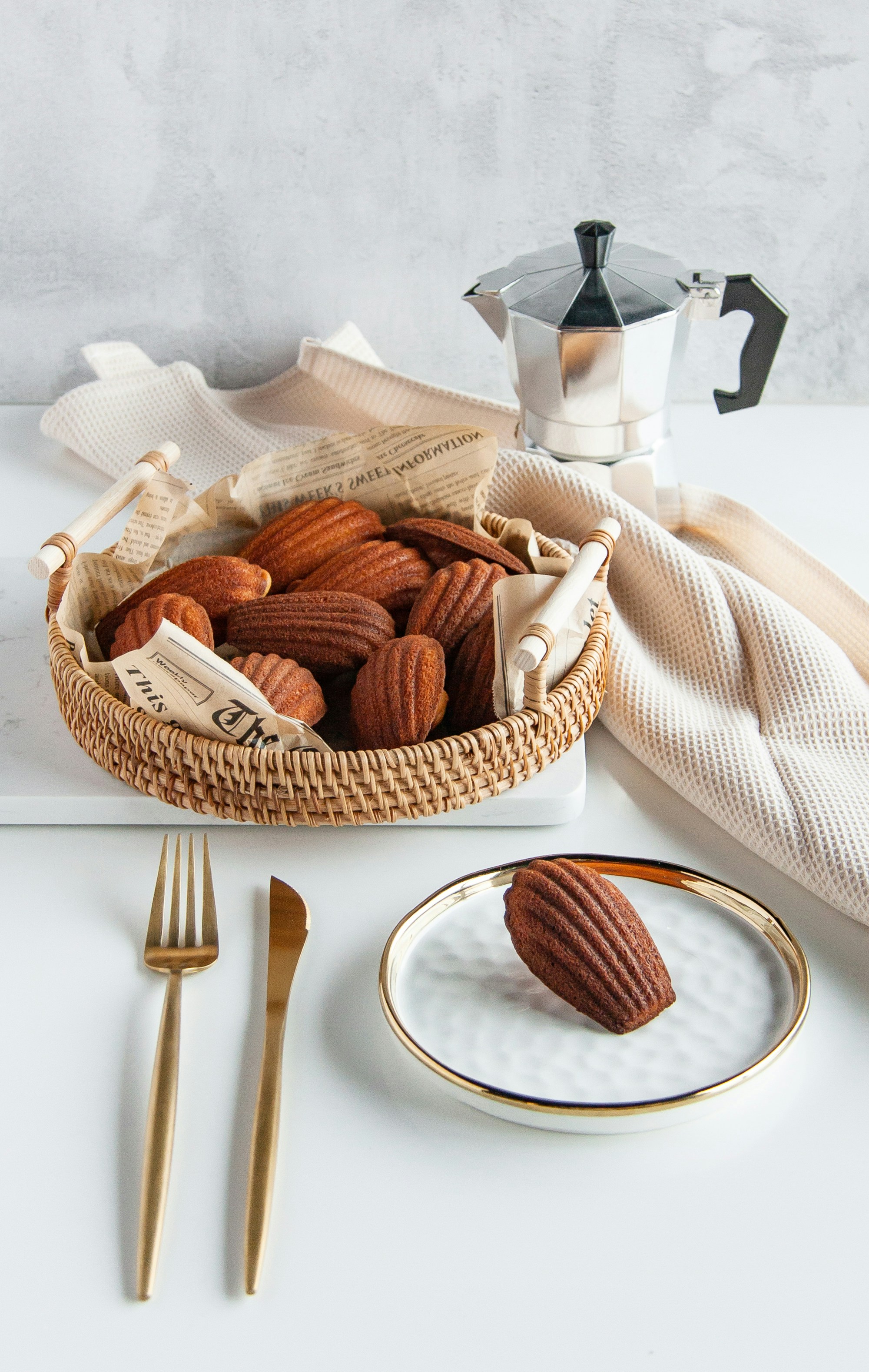 Three chocolate madeleines on marble board with honey pot, warm golden light from above