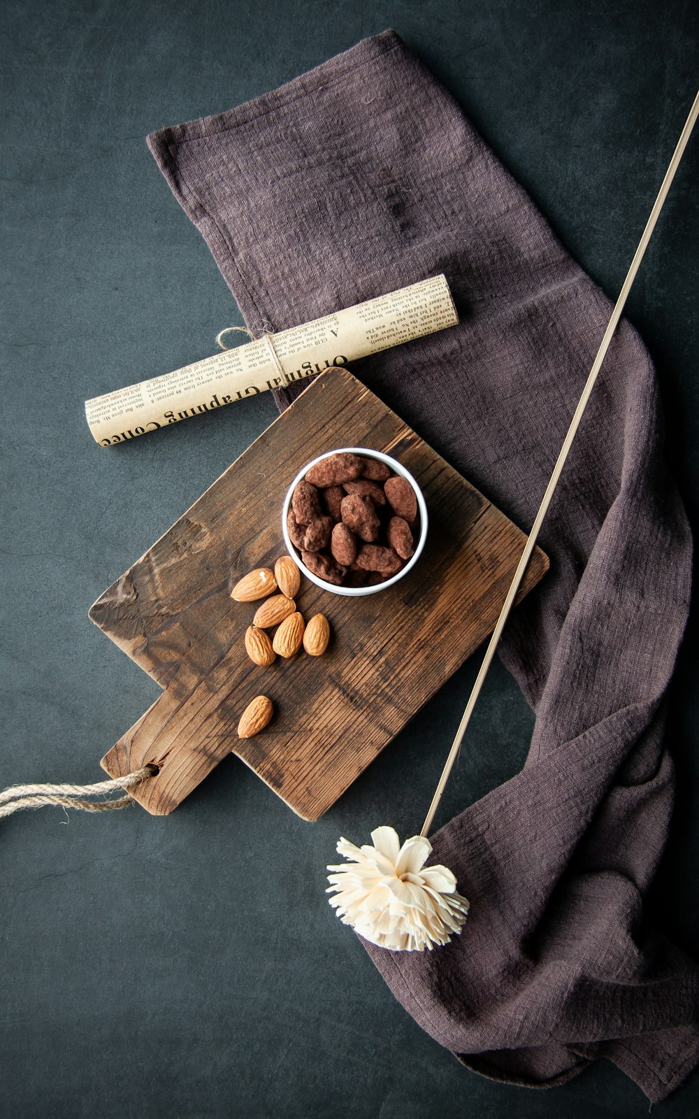 a wooden cutting board topped with a bowl of nuts