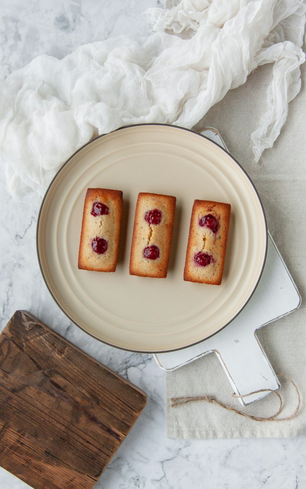 three pieces of cake sitting on a plate next to a cutting board