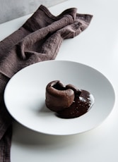 a white plate topped with two chocolate donuts
