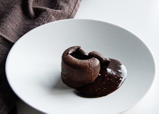 a white plate topped with two chocolate donuts