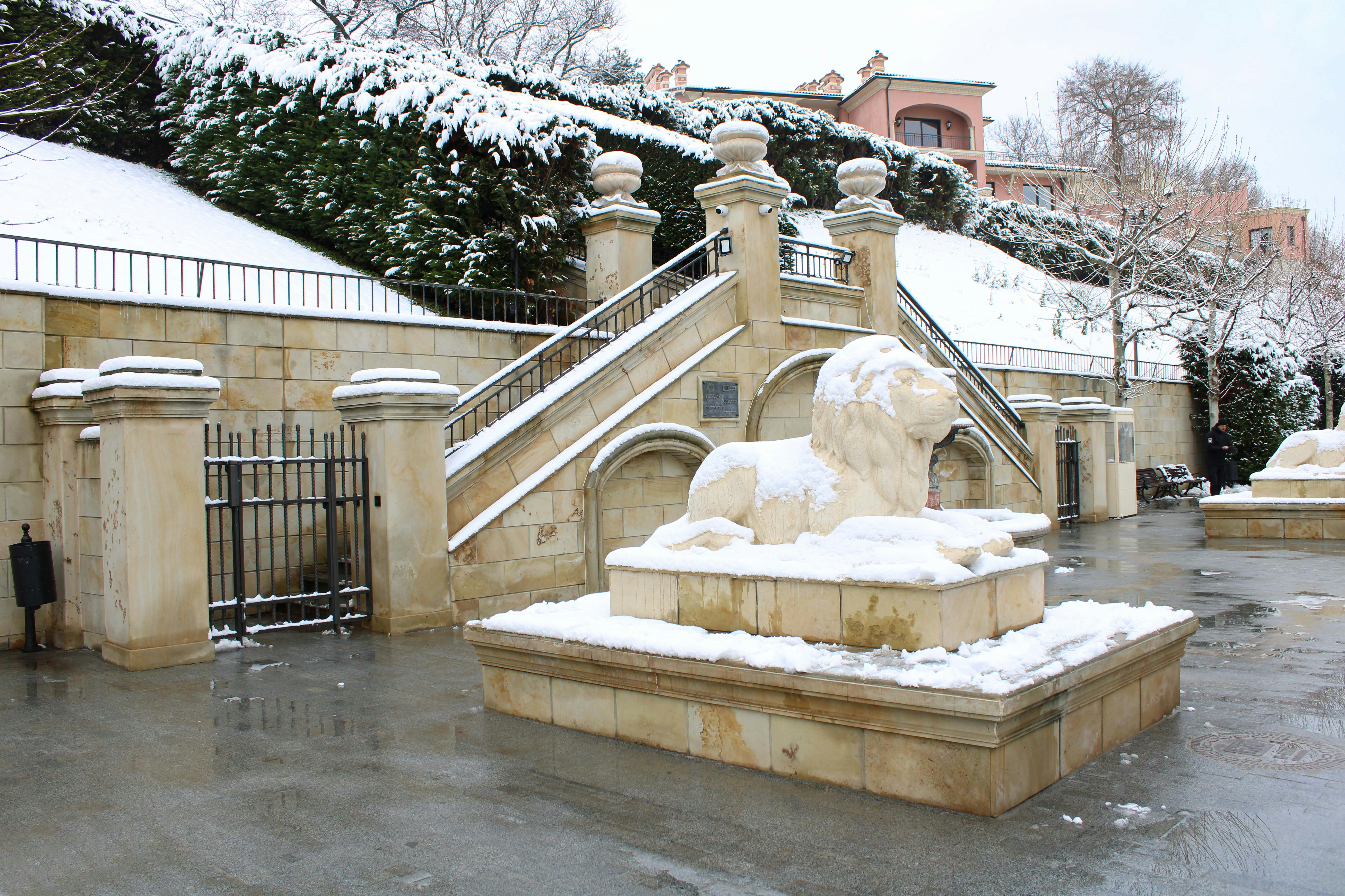 a statue of a lion in front of a building covered in snow
