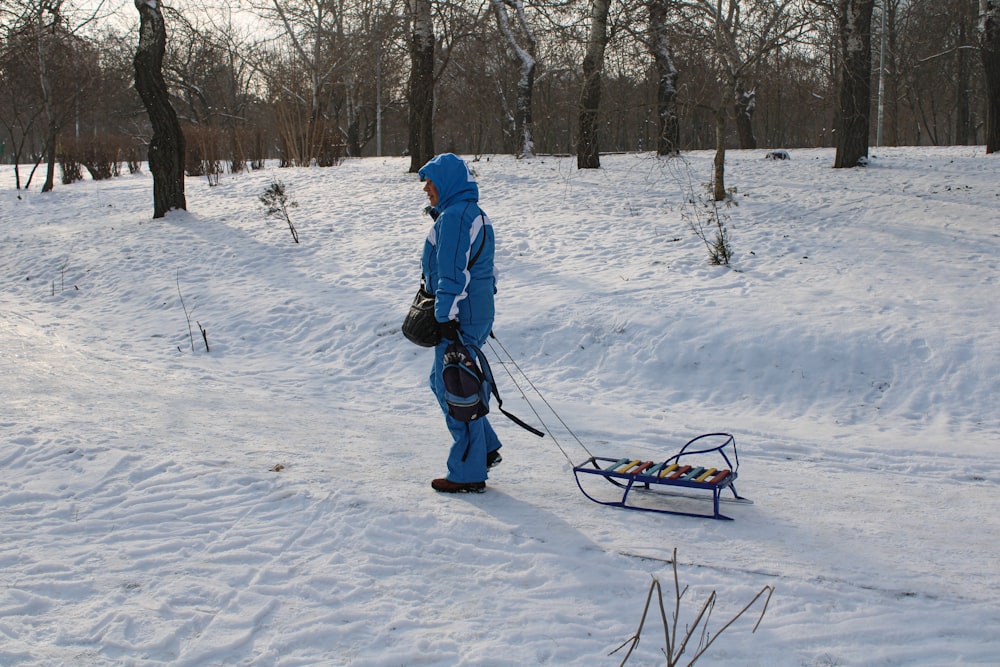 a person in a blue snow suit pulling a sled