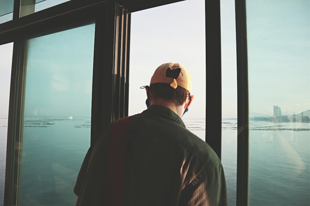 a man looking out a window at the ocean