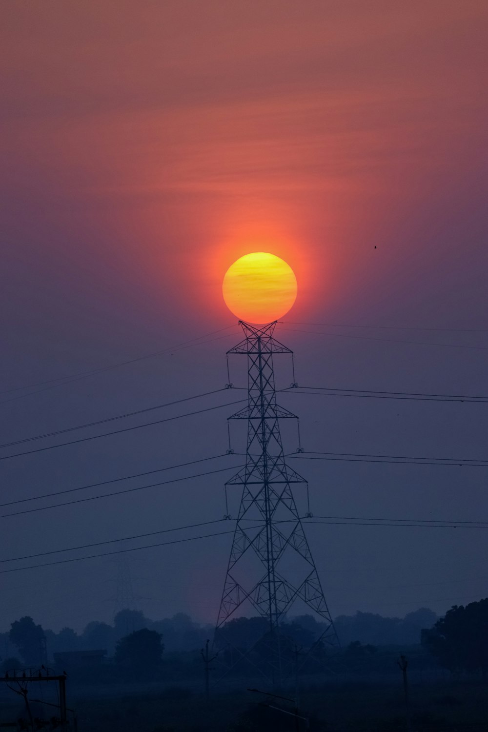 the sun is setting behind a power line
