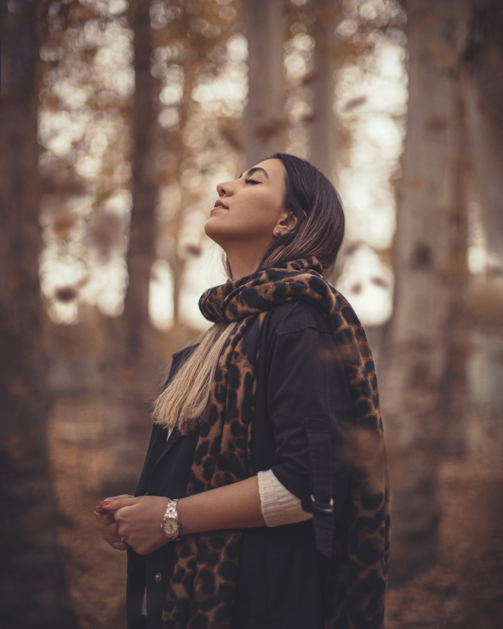 a woman standing in a forest with her eyes closed