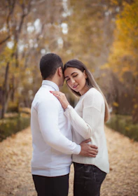 a man and a woman standing together in the woods