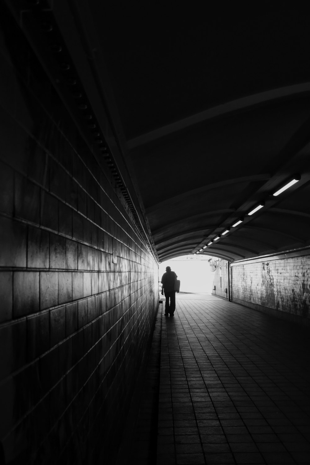 a person walking down a tunnel with a light at the end