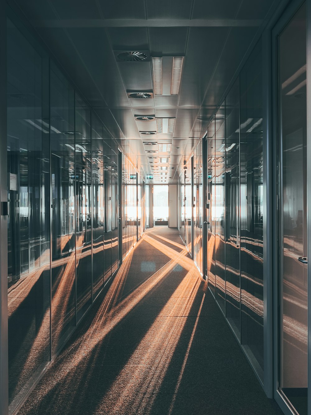 a long hallway with mirrored walls and light coming through the windows