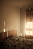 Bedroom with crisp white linens, a light wood headboard, and a pendant light hanging above.