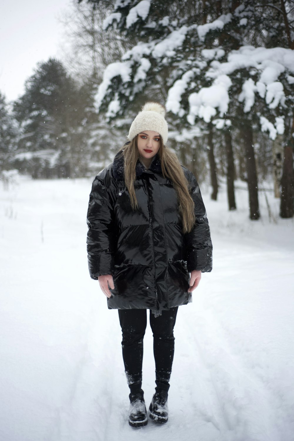 a woman standing in the snow wearing a black coat