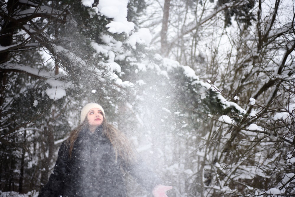 Eine Frau steht im Schnee vor einem Baum