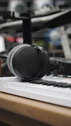 A producer working on a beat with headphones in an olive-toned studio