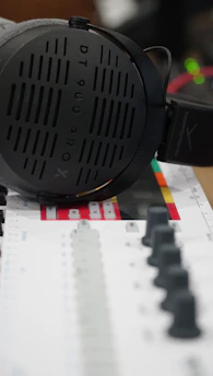 Close-up of headphones resting on a mixing console with colorful sound waves in the background.