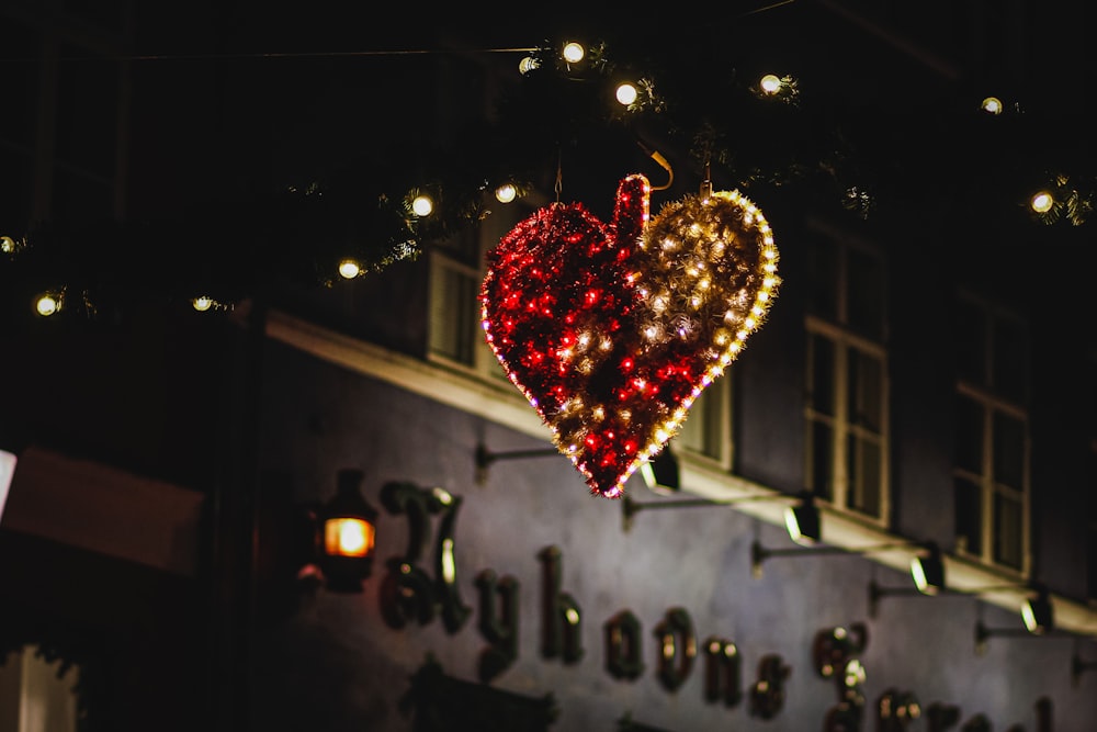 a lighted heart hanging from the side of a building