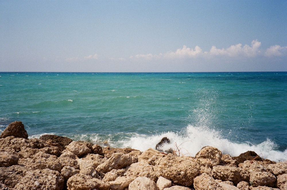 a person sitting on a rock near the ocean