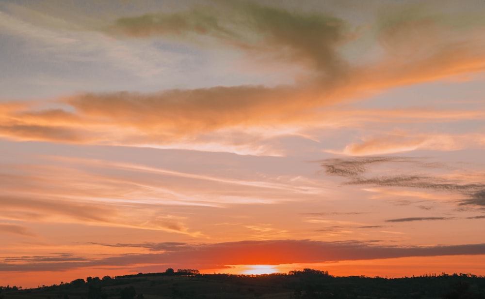 the sun is setting over a field with trees