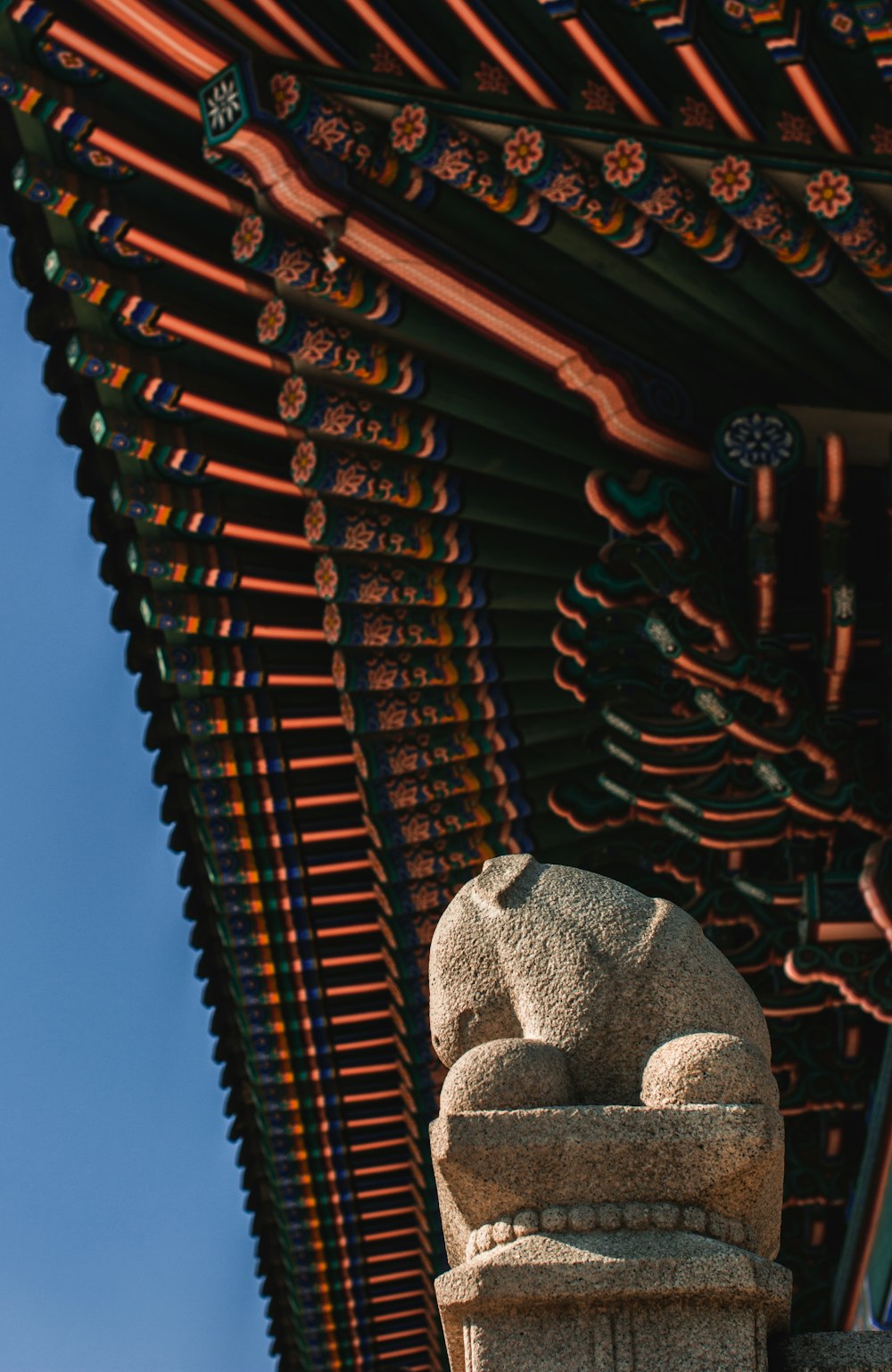 a stone statue sitting under a roof under a blue sky