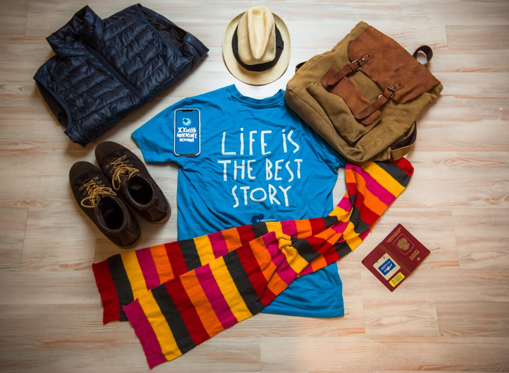 a shirt that says life is the best story next to a hat, scarf,