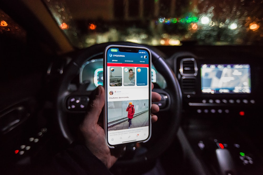 a person holding a cell phone in a car