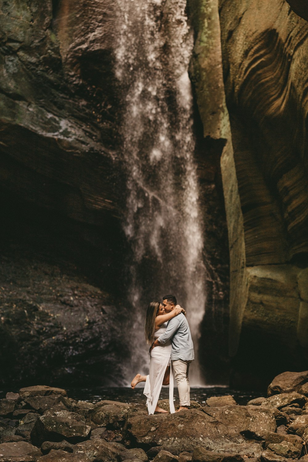 a couple embracing in front of a waterfall